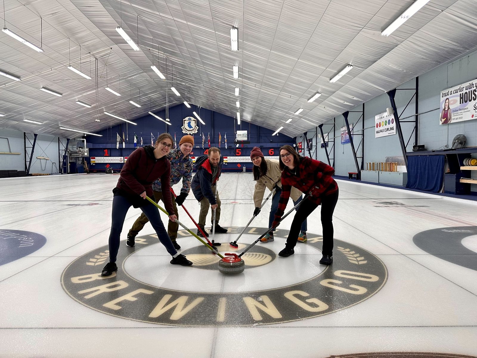 Five lab members sweeping a curling stone on the ice